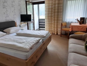 Habitación de hotel con cama, televisor, balcón, sofá y mesa con un adorno.