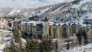 A multi-story hotel with a central courtyard, surrounded by snow-covered mountains and trees.