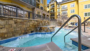 A pool area with a hot tub, stone walls, and a no diving sign.