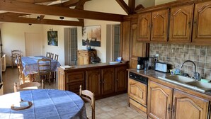 A kitchen with wooden cabinets, a dining table with chairs, and a kitchen island with a sink and appliances.