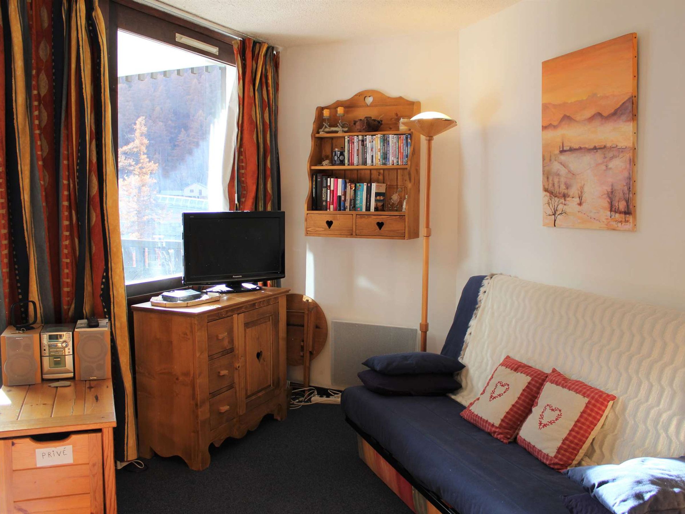 Une pièce confortable avec un bureau en bois, une télévision, une bibliothèque et un canapé.