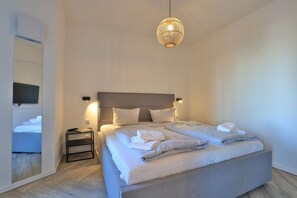 Une chambre à coucher moderne avec un grand lit, des tables de chevet, un téléviseur à écran plat et un luminaire sphérique original.