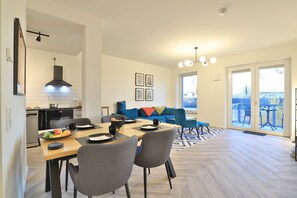 Une cuisine moderne avec un coin repas, un canapé bleu et une vue sur la ville grâce à de grandes fenêtres.