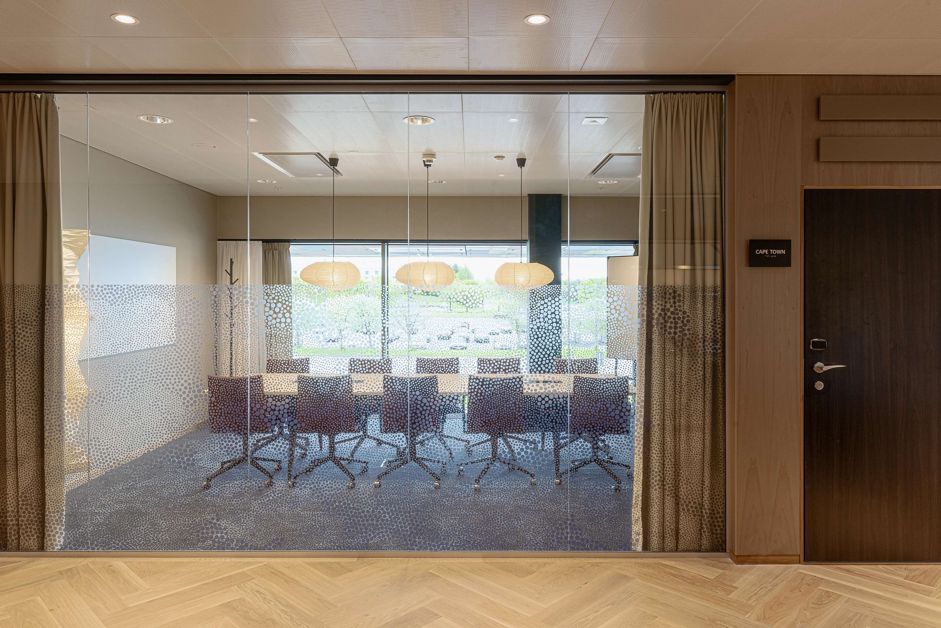 Un salón de conferencias con paredes de vidrio, piso de madera y una puerta con la inscripción 'Cape Town'.
