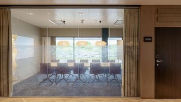 Un salón de conferencias con paredes de vidrio, piso de madera y una puerta con la inscripción 'Cape Town'.