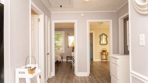 A hallway with white walls and wooden flooring, leading to a room with a bed and a chair. - In the Heart of the Sandhills (Aberdeen)