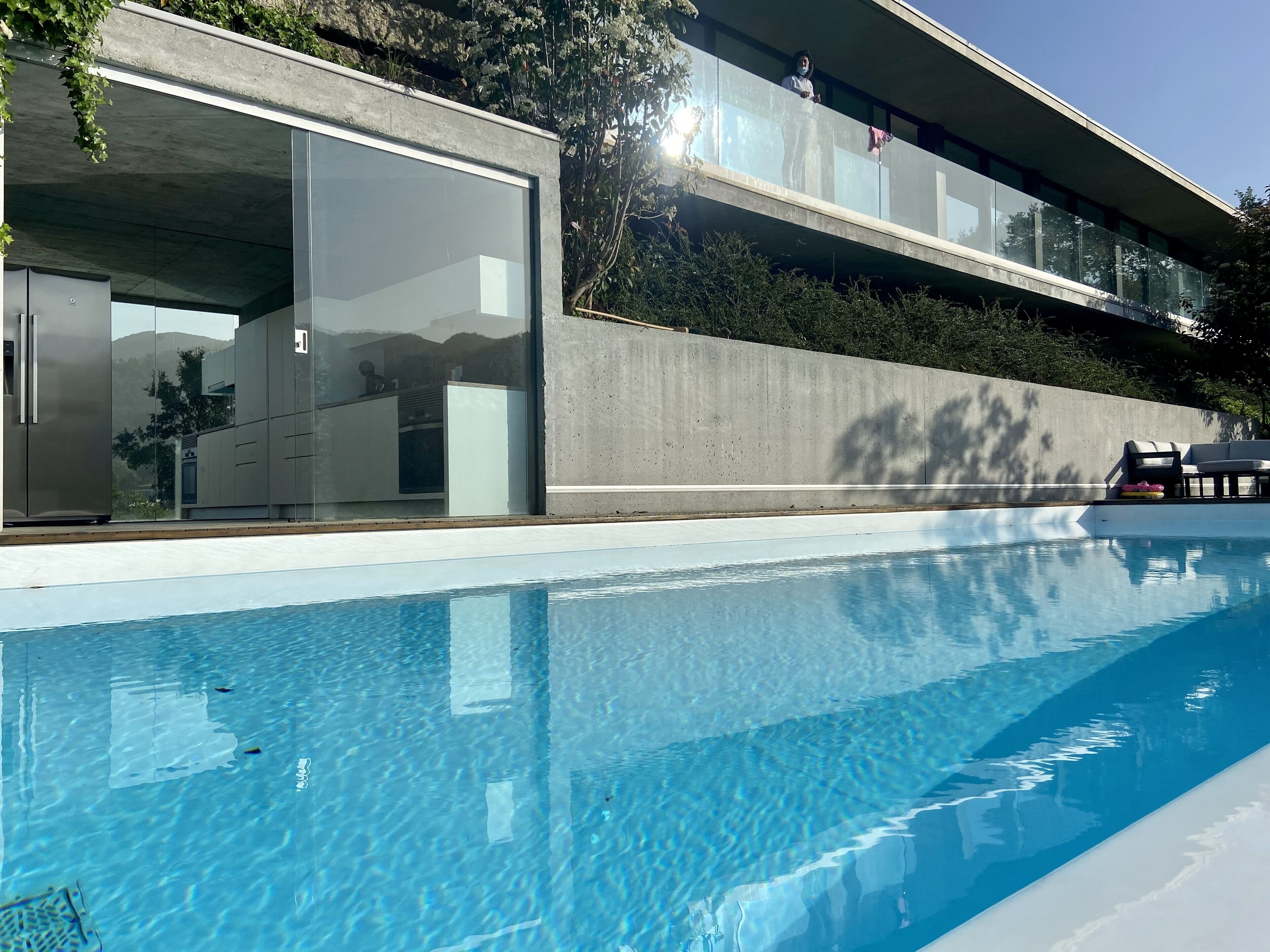Un bâtiment moderne doté d’une piscine, de grandes baies vitrées et d’une façade en béton.
