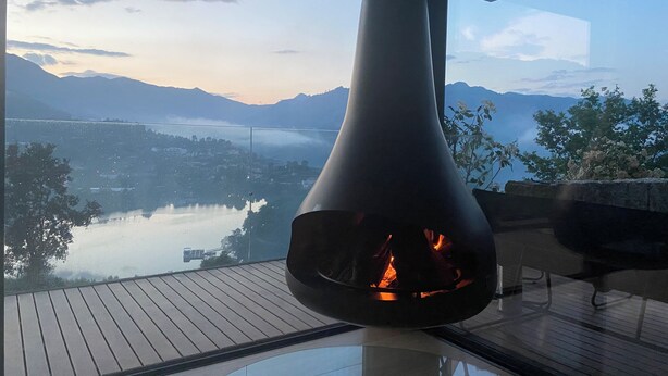 Una chimenea moderna con una vista panorámica de un lago y montañas.