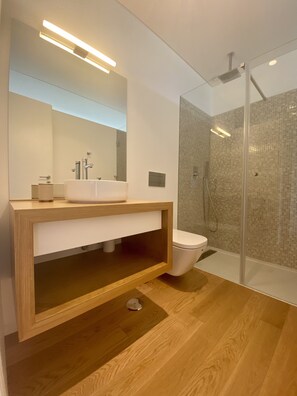 A modern bathroom with a wooden vanity, a white sink, a mirror, a toilet, and a glass-enclosed shower. - Villa Individuelle Avec Piscine / Terrain, vue - Gères - Caniçada - Rio Cavado (Ventosa)