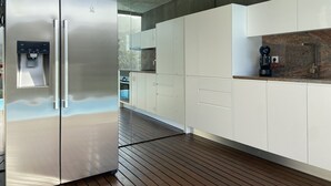 Una cocina moderna con refrigerador de acero inoxidable, armarios blancos y dispensador de agua.