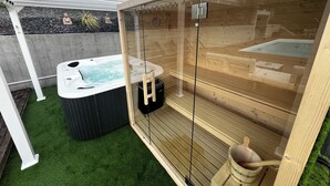 Una sauna de madera con puertas de vidrio, un jacuzzi y un banco de madera.