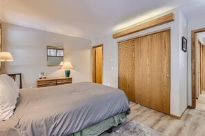 A bedroom with a large bed, a dresser, a mirror, and a wooden wardrobe. - Creek Condos C-1 3 Bedroom Condo by RedAwning (Frisco)