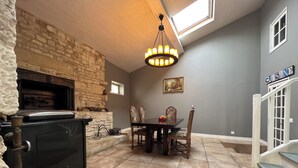 Un comedor con chimenea de piedra, una araña y una mesa con sillas.