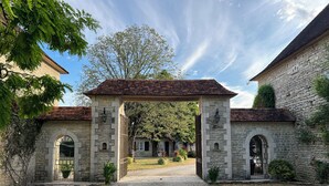 Un edificio de piedra con un camino de grava que conduce a un porche cubierto.