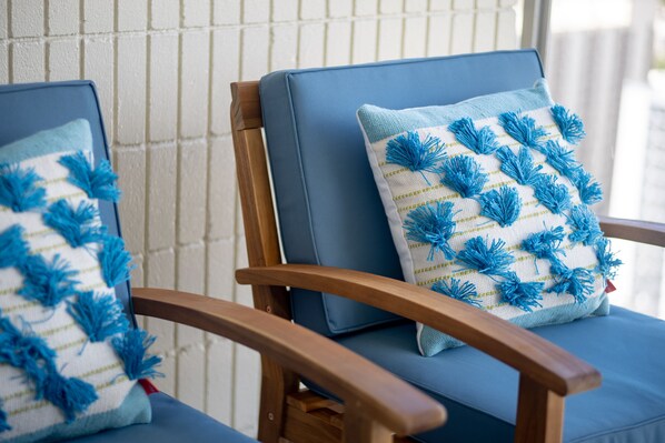 Two wooden chairs with blue cushions and blue tassel pillows.