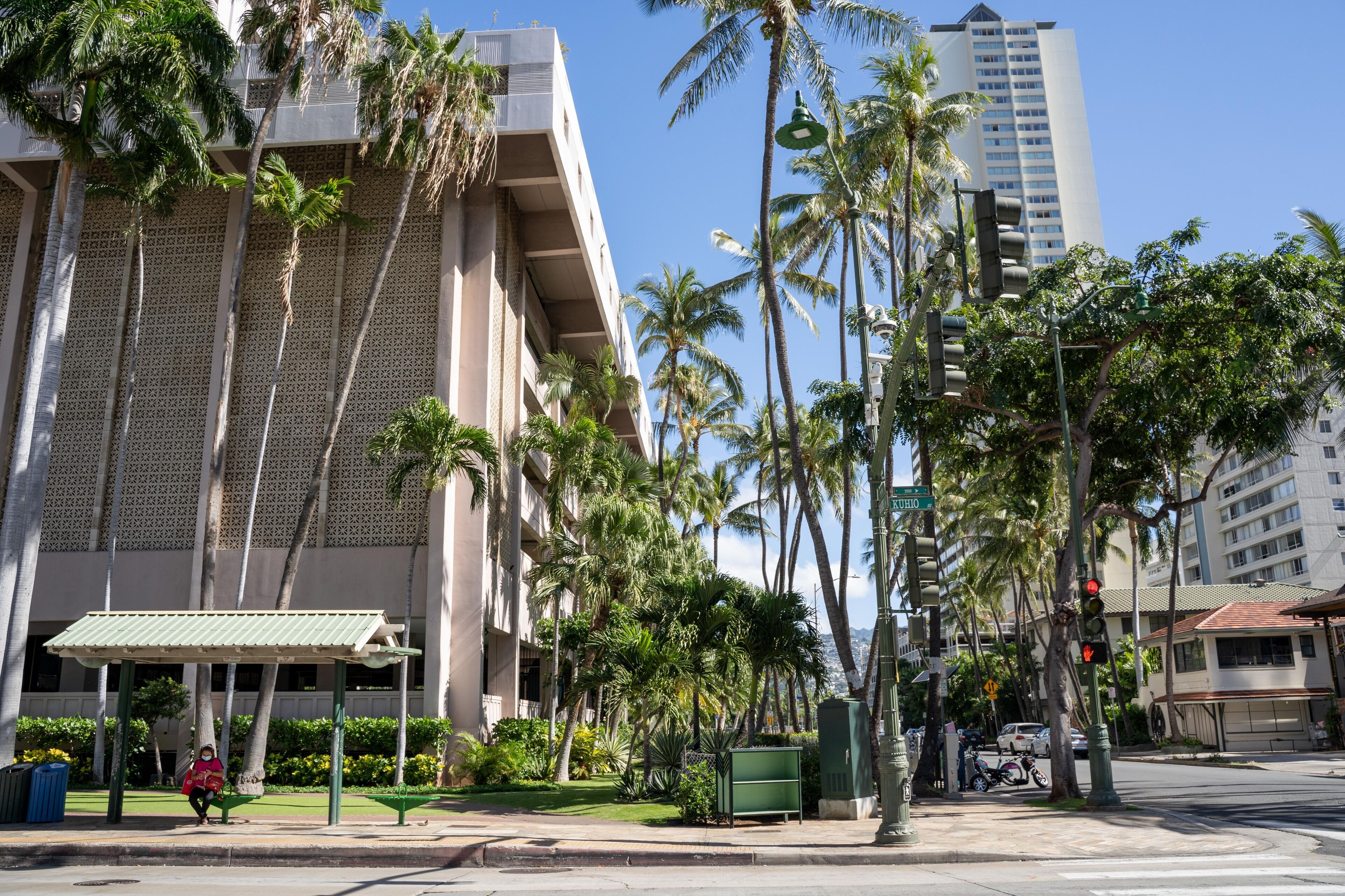 A building with a patterned facade, a covered seating area, and palm trees.