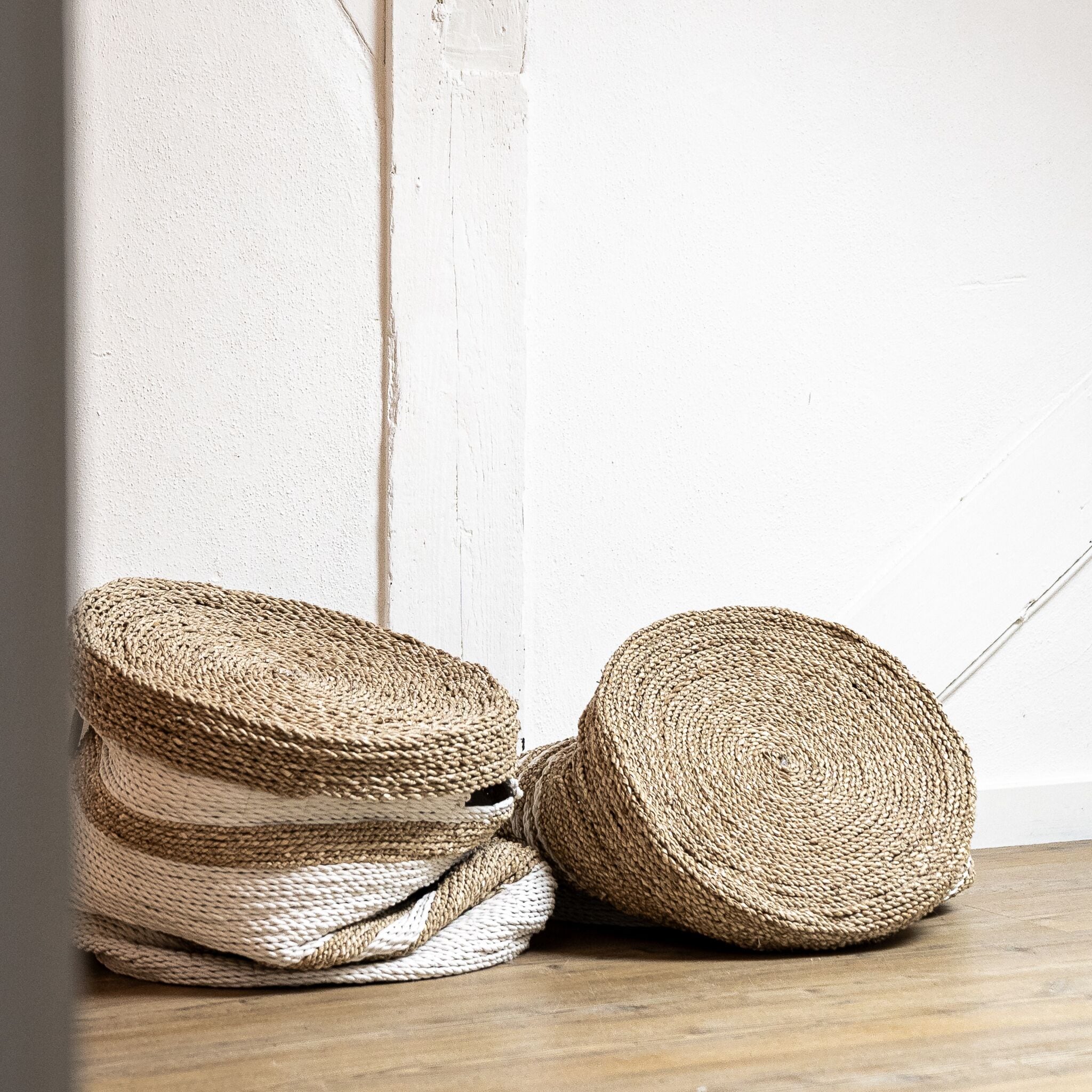Deux paniers tressés adossés à un mur blanc.