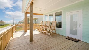 A wooden deck with outdoor seating and a door to a building with light green siding. - Sea Bliss - 3 bedroom, 2 bath home that sleeps 8 - Easy Beach Access! (Crystal Beach)