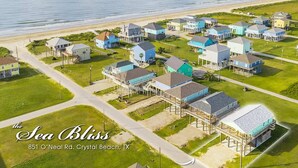An aerial view of a coastal residential area named "the Sea Bliss" with houses on stilts, located at 851 O'Neal Rd., Crystal Beach, TX. - Sea Bliss - 3 bedroom, 2 bath home that sleeps 8 - Easy Beach Access! (Crystal Beach)