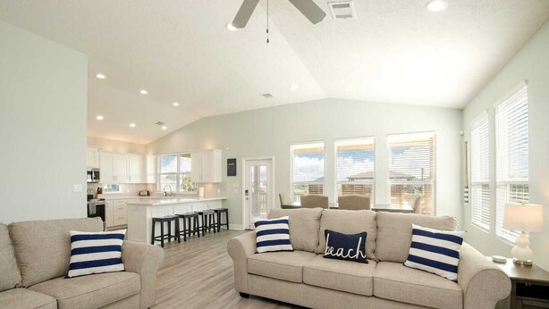 A spacious living room with a large sofa, a coffee table, and a kitchen area in the background. - Sea Bliss - 3 bedroom, 2 bath home that sleeps 8 - Easy Beach Access! (Crystal Beach)