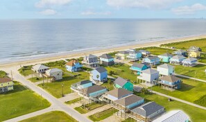 An aerial view of a coastal residential area named "the Sea Bliss" with houses on stilts, located at 851 O'Neal Rd., Crystal Beach, TX.