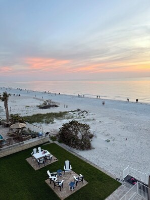 Uitzicht op een strand met een terras en buitenmeubilair, inclusief een zwembad.