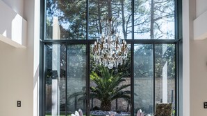 A dining area with a table set for six, large windows, and a view of a garden. - Beautiful contemporary villa between lake and ocean. Free wifi. (Soorts-Hossegor)