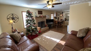 A living room with a fireplace, a Christmas tree, a ceiling fan, and a dining area. - Beautiful Country Home on 11 Acres Near Toledo Bend Lake. (Milam)