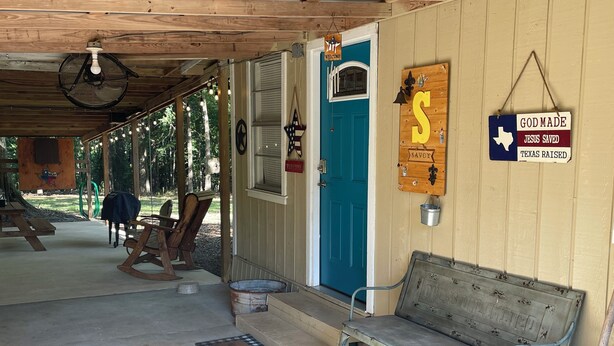 A rustic cabin with a blue door, a welcome sign, and a bench. - Beautiful Country Home on 11 Acres Near Toledo Bend Lake. (Milam)