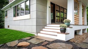 A modern house with a stone pathway leading to a set of steps, a small garden, and a wooden fence. - Marblehead. Cottage on Whittier, new construction (Marblehead)