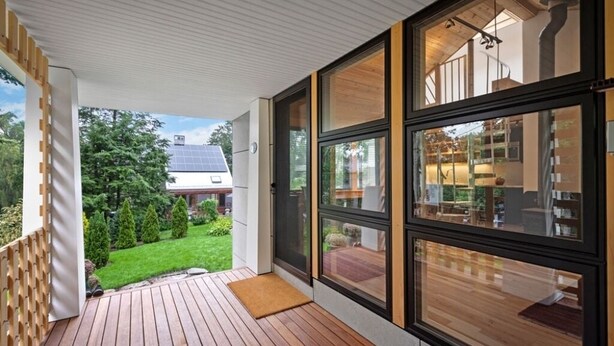 A modern house with a wooden deck, large windows, and a view of a garden and neighboring buildings. - Marblehead. Cottage on Whittier, new construction (Marblehead)