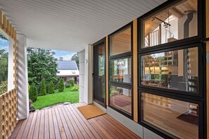 A modern house with a wooden deck, large windows, and a view of a garden and neighboring buildings. - Marblehead. Cottage on Whittier, new construction (Marblehead)
