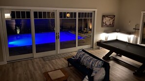 Ein Wohnzimmer mit Blick auf einen Pool, einem Billardtisch und einem Sofa.
