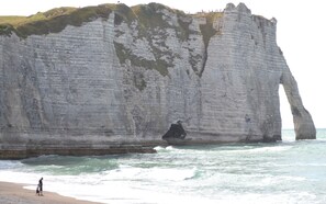 Stand at the base of this dramatic limestone cliff, where the ocean's waves crash against the shore.