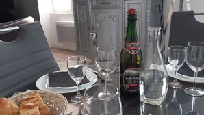 Ruokapöytä on katettu viinilaseilla, pöydällä on pullo brettonilaista kuivaa siideriä (Cidre Breton Brut) ja kori täynnä leipää.