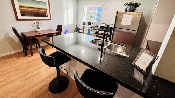 A modern kitchen with a central island, stainless steel appliances, and a dining area with chairs. - Mo`s Mid-Town 2Bdrm Marvel 103 (Phoenix)