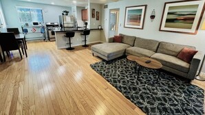 A modern living room with a sofa, coffee table, and a kitchen area with appliances. - Mo`s Mid-Town 2Bdrm Marvel 103 (Phoenix)
