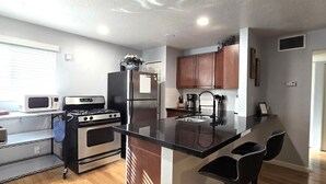 A modern kitchen with a central island, stainless steel appliances, and wooden cabinets. - Mo`s Mid-Town 2Bdrm Marvel 103 (Phoenix)
