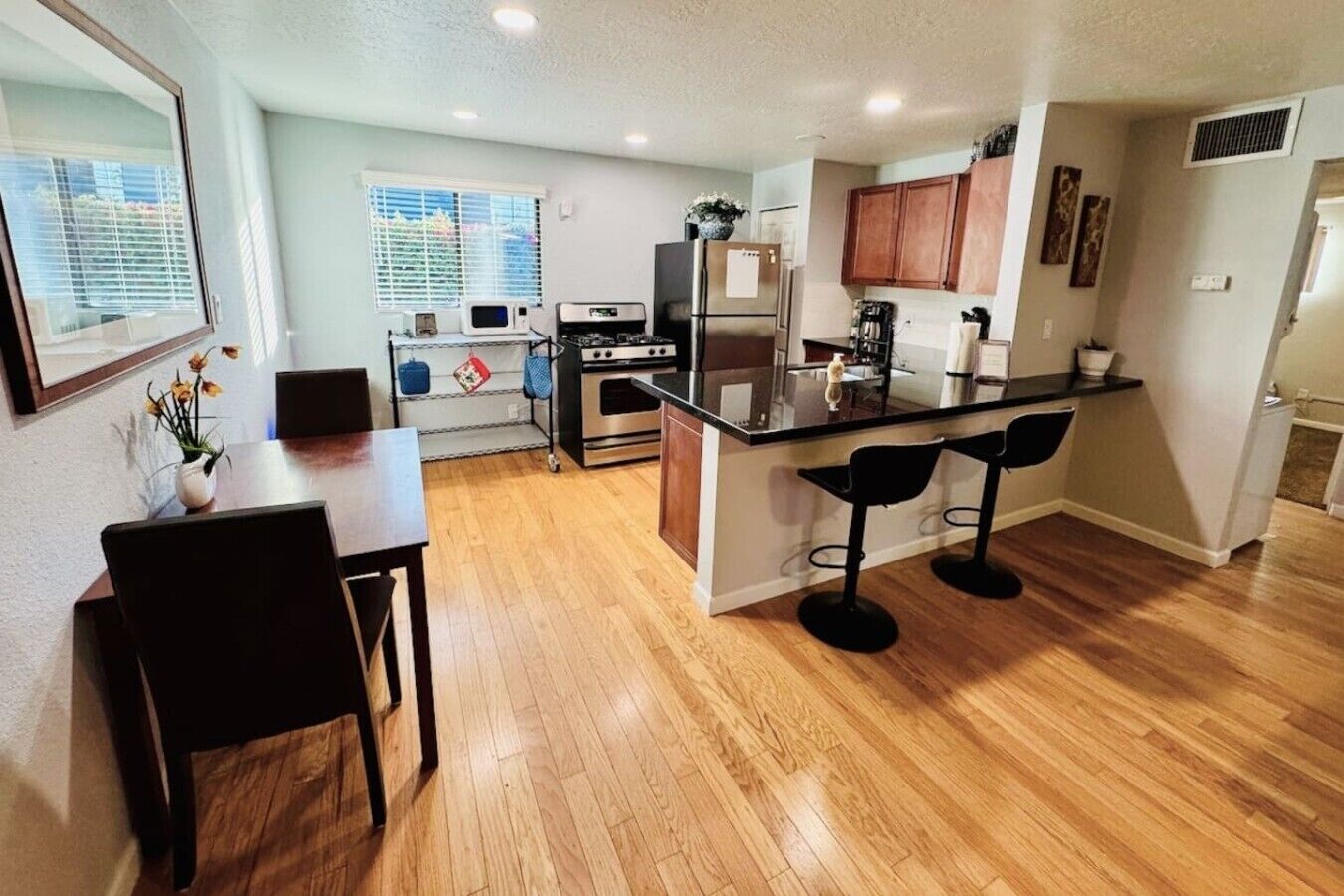A modern kitchen with a central island, bar stools, and a dining table with chairs.