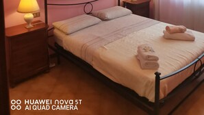 A bedroom with a bed, two bedside tables with lamps, a painting on the wall, and a window with curtains. - Villetta Camelia with private parking just a stone's throw from Lucca (Capannori)