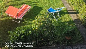 A well-maintained garden with a slide, a red and white lounge chair, and a blue folding chair. - Villetta Camelia with private parking just a stone's throw from Lucca (Capannori)