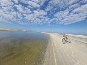 A bicycle parked on a sandy beach with a clear sky.