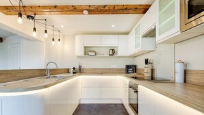 A modern kitchen with white cabinetry, a wooden countertop, and a built-in oven.