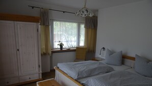 Une chambre à coucher comprenant un lit, un banc, une fenêtre avec des rideaux, un radiateur et une armoire.