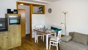Un espace de vie compact comprenant un coin cuisine, un coin repas et un coin salon.