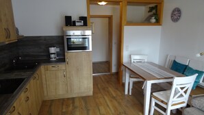 Une cuisine compacte dotée d’un four encastré, d’une machine à café et de meubles de rangement en bois.