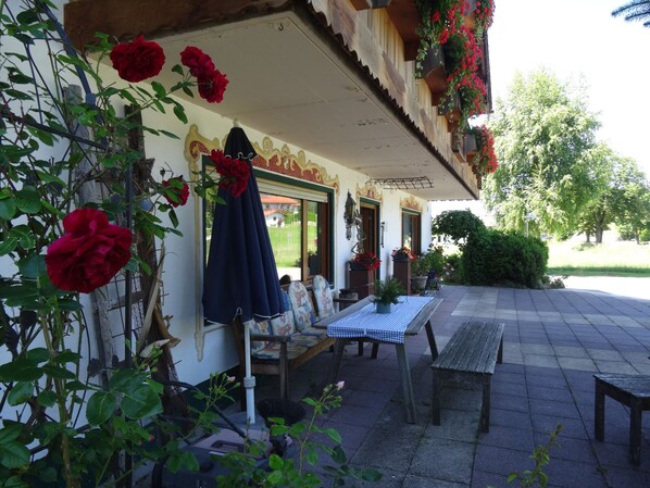 A patio with a table and benches, surrounded by potted plants and flowers.