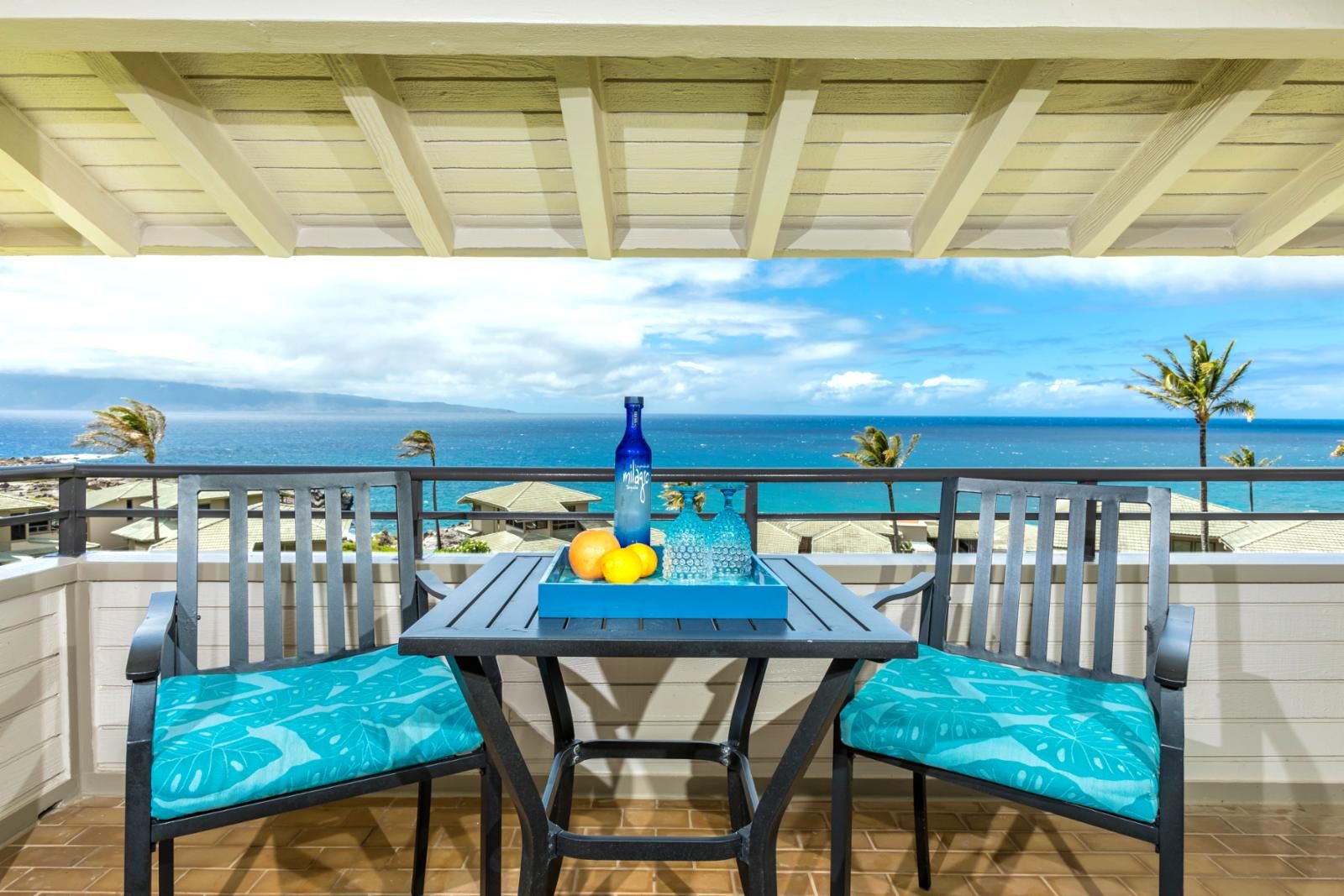 A balcony with a table, chairs, and a view of the ocean.