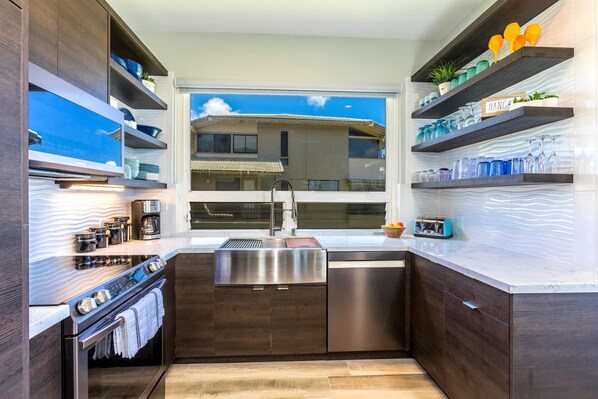 A modern kitchen with dark wood cabinets, stainless steel appliances, and a window with a view of a building.