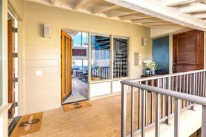 A modern house with a wooden door, a glass door leading to a balcony, and a welcome mat.